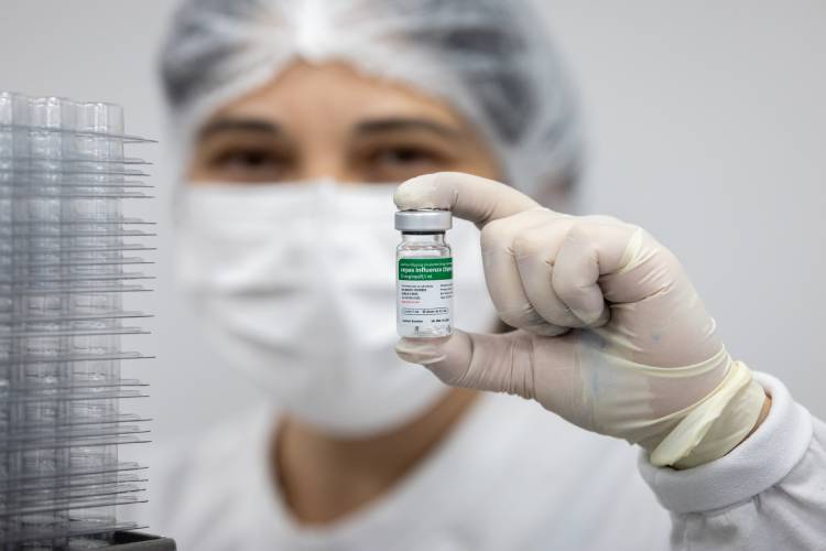 Mulher segura frasco de vacina da gripe do Butantan